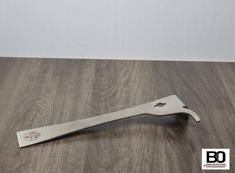 May include: A stainless steel beekeeping hive tool with a curved end, a hook, and a hole. The tool has a flat, elongated body with a logo on the handle. The tool is designed for hive maintenance.