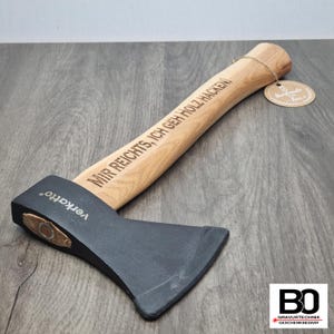 Könnte beinhalten: Eine schwarze Axt mit einem Holzstiel. Der Stiel ist mit dem Text "Mir reicht's, ich geh Holz hacken!" und der Marke "Verkortho" graviert.