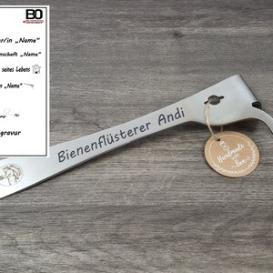 May include: A stainless steel beekeeping hive tool with the text "Bienenfl&uuml;sterer Andi" engraved on the handle. A small, round tag with "Handmade with love" is attached. A selection of engraving options is shown in the upper left.