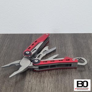 Op de afbeelding: Een rood en zilver multi-tool met tang, flesopener en andere gereedschappen. De multitool is gedeeltelijk open, waarbij de verschillende functies worden weergegeven. De handgreep is rood en de gereedschappen zijn zilver.