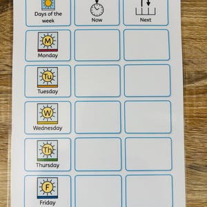 May include: A white laminated chart featuring a grid with blue borders. The first column lists days of the week from Monday to Friday with sun icons and letters. The top row includes headers for Days of the week, Now, and Next. Text includes Widgit symbols.
