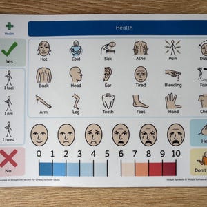 May include: A laminated health communication board with the word "Health" at the top. It features visual symbols for various symptoms like "Hot," "Cold," and "Pain," along with a pain scale from 0 to 10. Includes "Yes," "No," and "Don't know" options.