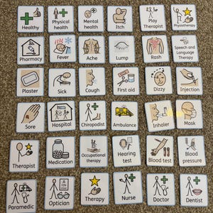 May include: A set of square cards with medical-themed illustrations and text. The cards display images and words such as "Healthy," "Pharmacy," "Cough," "Injection," and "Doctor." The cards are laid out on a brown surface.