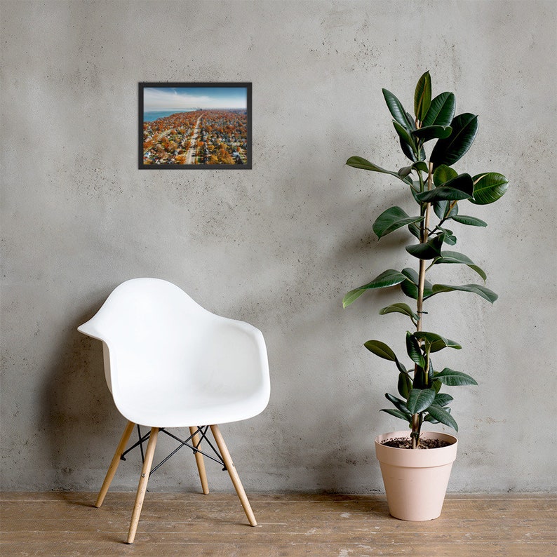May include: An aerial photograph of a residential neighborhood with houses and trees in autumn colors. The photo is framed in a black frame.
