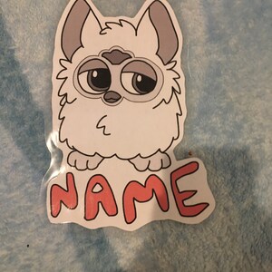 May include: A white furry cartoon character with big eyes and a pink nose. The character is standing on its hind legs and has the word "NAME" written in red below it.