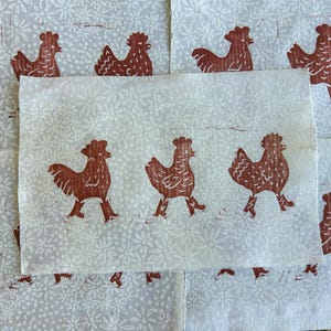 May include: Multiple fabric squares featuring a repeating pattern of brown rooster illustrations on a light grey background with a floral design. The roosters are depicted walking.