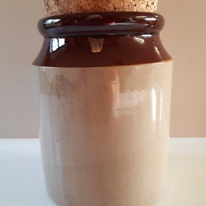 Peut inclure: Un pot en c&eacute;ramique brun et beige avec un couvercle en li&egrave;ge. Le pot est recouvert d'un glacis brun sur le dessus et d'un glacis beige sur le dessous.