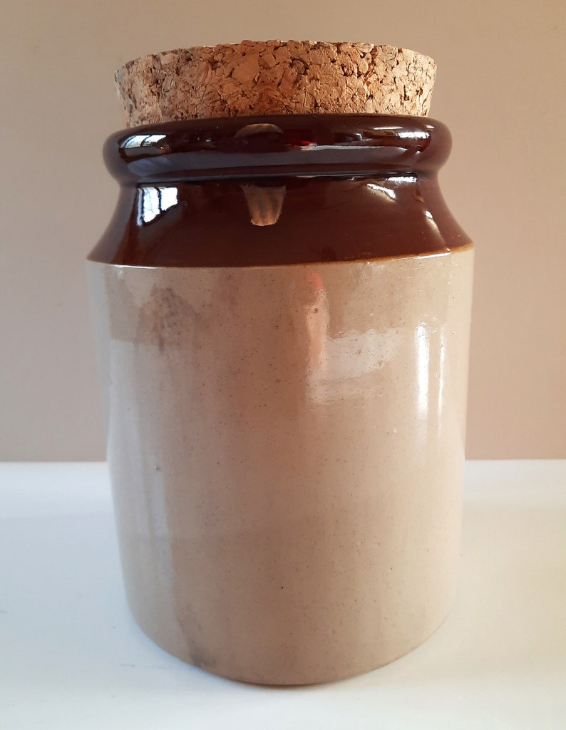 Peut inclure: Un pot en c&eacute;ramique brun et beige avec un couvercle en li&egrave;ge. Le pot est recouvert d'un glacis brun sur le dessus et d'un glacis beige sur le dessous.