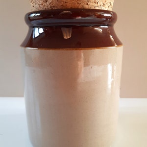 Peut inclure: Un pot en c&eacute;ramique brun et beige avec un couvercle en li&egrave;ge. Le pot est recouvert d'un glacis brun sur le dessus et le dessous et d'un glacis beige au milieu.