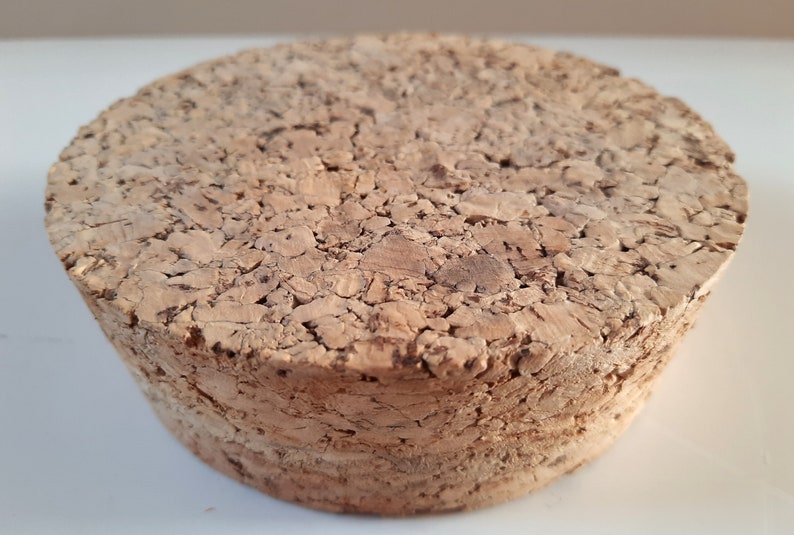 Peut inclure: Un bouchon de li&egrave;ge rond et brun avec une surface rugueuse et textur&eacute;e.