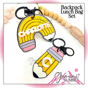 May include: Two pencil-themed keychains with black metal rings. One is an arched pencil shape with the name CHARLOTTE in white letters. The other is a straight pencil shape with the letter C in white. Text reads Backpack Lunch Bag Set.