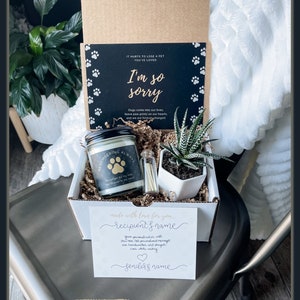 May include: A white gift box with a black card that says "I'm so sorry" with paw prints. The box contains a candle, matches, and a succulent plant. The card also says "made with love for you..." and has space for a recipient's name and sender's name.