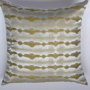 May include: A decorative throw pillow with a white and gold striped pattern. The pillow is made of a soft, plush fabric and has a subtle sheen.