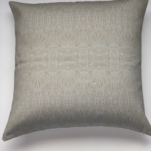 May include: A beige throw pillow with a geometric pattern. The pattern is a light beige on a slightly darker beige background.