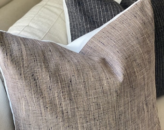 May include: Three decorative throw pillows with a striped pattern. The pillows are made of a textured fabric with a subtle sheen. The pillows are arranged in a stack, with the largest pillow on the bottom and the smallest pillow on top.