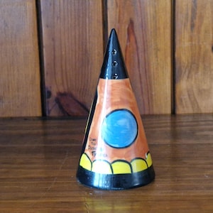 May include: A ceramic cone-shaped salt and pepper shaker with a black, orange, yellow, and blue design. The shaker has a black top with three holes and the text "Dawn Hill Designs" on the side.