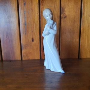 Nao figurine of a girl with dog. A young girl holding her puppy in her arms.