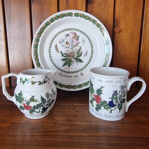 May include: A white ceramic plate, mug, and pitcher with a green and white floral design. The plate has the text "Christmas 1993" on it. The mug has the text "things are both full of grace" on it.