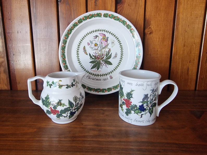 May include: A white ceramic plate, mug, and pitcher with a green and white floral design. The plate has the text "Christmas 1993" on it. The mug has the text "things are both full of grace" on it.