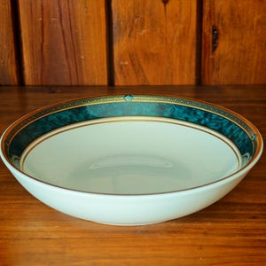 Peut inclure: Un saladier en c&eacute;ramique blanche avec une bordure d&eacute;corative turquoise et dor&eacute;e. Le bol est rond et pos&eacute; sur une surface en bois. La bordure turquoise a un effet marbr&eacute; et est orn&eacute;e d'une garniture dor&eacute;e.
