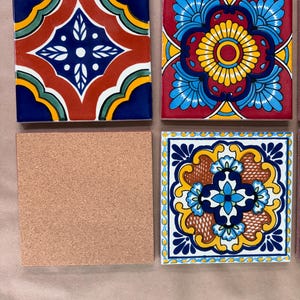 May include: Four square ceramic tiles with colorful, intricate designs. Two tiles feature floral patterns in red, blue, yellow, and white. One tile is plain cork. The fourth tile has a geometric design with red, blue, and white elements.