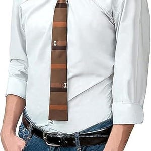 Puede incluir: Una camisa blanca abotonada con una corbata a rayas marrón y beige con detalles blancos. La camisa se combina con vaqueros azules y un cinturón negro. Un atuendo de estilo business casual clásico.