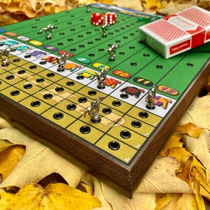 May include: A wooden game board with a green race track and gold squares.  The board has 12 numbered spaces and a deck of cards.  There are silver horses with jockeys on the board.