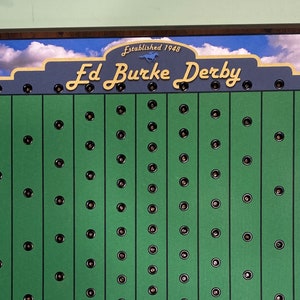 May include: A green board with the text "Ed Burke Derby" and the words "Established 1948" above it. The board has a grid of black circles.