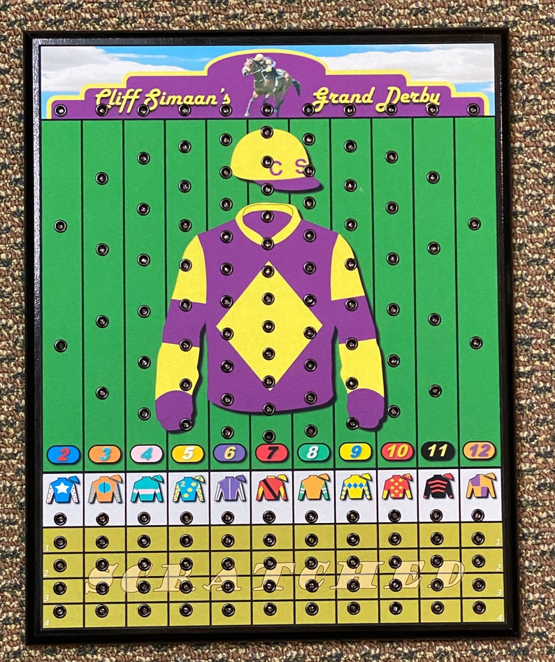 May include: A wooden game board with a green background and a purple jockey's uniform with yellow accents. The board has 12 numbered spaces and a horse racing theme. The text "Cliff Simaaan's Grand Derby" is at the top of the board.
