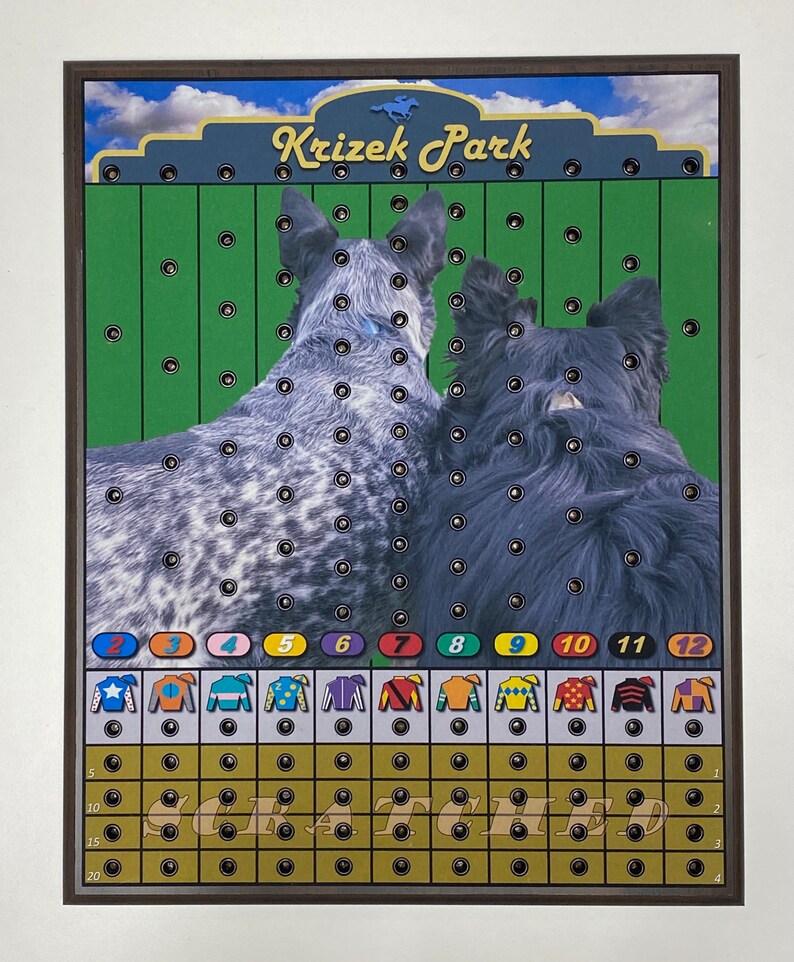 May include: A game board with a green background and a wooden frame. The board features a race track with 12 numbered spaces. The game is called "Krizek Park" and features two dogs in the background. The game board has a grid of holes for players to drop marbles into.