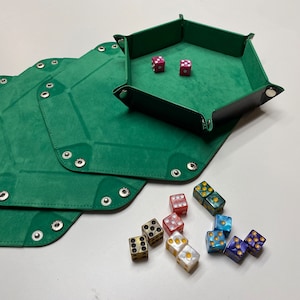 May include: Green dice rolling trays with a hexagonal shape, and several dice in various colors. The trays are made of a soft, suede-like material and have snap closures. Two red dice are inside one tray.