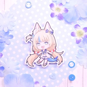 May include: A sticker featuring a cartoon character with fox-like ears, wearing a sailor-style outfit with a blue tail. The character has blonde hair with blue highlights and is surrounded by blue and purple flowers and buttons on a polka-dot background.
