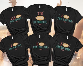 Puede incluir: Seis camisetas negras con texto blanco y detalles coloridos. Las camisetas presentan frases humorísticas sobre el divorcio, incluyendo "Finalmente estoy divorciada", "Ayudé a mudarse", "Le rayé el coche", "Llamé al abogado", "Voy a comprar las bebidas" y "Nunca me gustó".