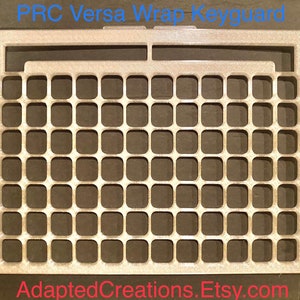 May include: A silver metal keyguard with a grid pattern. The keyguard is designed to fit a PRC Versa Wrap keyboard. The text "PRC Versa Wrap Keyguard" is printed at the top of the image. The text "AdaptedCreations.Etsy.com" is printed at the bottom of the image.