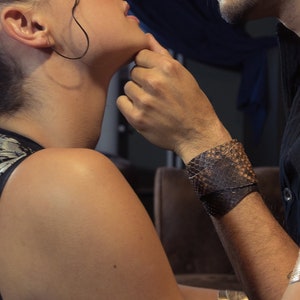 Könnte beinhalten: Ein Paar, das sich anschaut, mit einer Nahaufnahme ihrer Gesichter. Die Frau trägt ein ärmelloses Oberteil mit einem strukturierten Muster und ein goldenes Armband. Der Mann trägt eine schwarze Lederjacke und ein goldenes Armband.