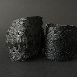 May include: Two black leather bracelets with a textured, snake-like pattern.