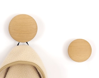 May include: Two wooden wall hooks with a light brown finish. One hook has a white fleece jacket hanging from it.