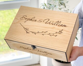 Peut inclure: Une boîte en bois avec un couvercle à charnières et un loquet en métal. La boîte est gravée des noms "Sophia & William" et d'un motif floral.