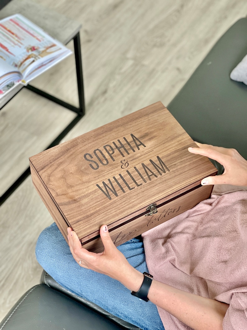 K&ouml;nnte beinhalten: Eine Holzkiste mit einem Scharnierdeckel, graviert mit den Namen "Sophia & William" und den Worten "Love Letters".