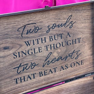 Pu&ograve; includere: Un cofanetto in legno scuro con l'iscrizione "Two souls with but a single thought two hearts that beat as one" in corsivo nero. Il cofanetto ha una cerniera in metallo e un accento rosa.