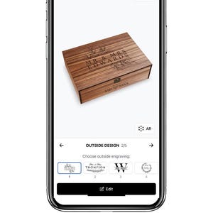 Pu&ograve; includere: Una scatola di legno con incisione personalizzata "MR & MRS EDWARDS" e decorazioni floreali. La scatola &egrave; visualizzata sullo schermo di uno smartphone, mostrando le opzioni di personalizzazione. Il sito web Boxpreview.com &egrave; visibile in basso.