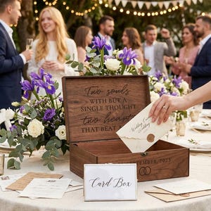 Pu&ograve; includere: Un portacarte in legno con l'iscrizione "Two souls with but a single thought, two hearts that beat". Una mano inserisce un biglietto di nozze nella scatola aperta. Un cartello "Card Box" &egrave; di fronte.