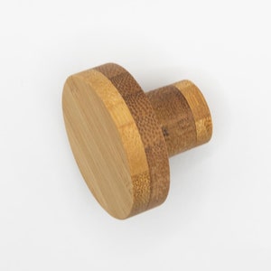 May include: A round, oval-shaped, wooden knob with a light brown color. The knob is made of bamboo and has a natural grain pattern.