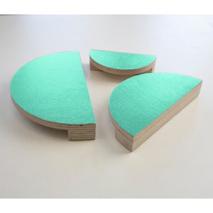 Op de afbeelding: Drie houten halve cirkelvormen in verschillende maten, geverfd in een heldere turquoise kleur. De vormen zijn gemaakt van multiplex en hebben een natuurlijke houtnerf afwerking aan de randen.