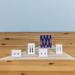 Expositor triangular de esquina con ranuras para tarjetas y joyas, ideal para comercios minoristas, ferias de artesanía y puestos de mercado.