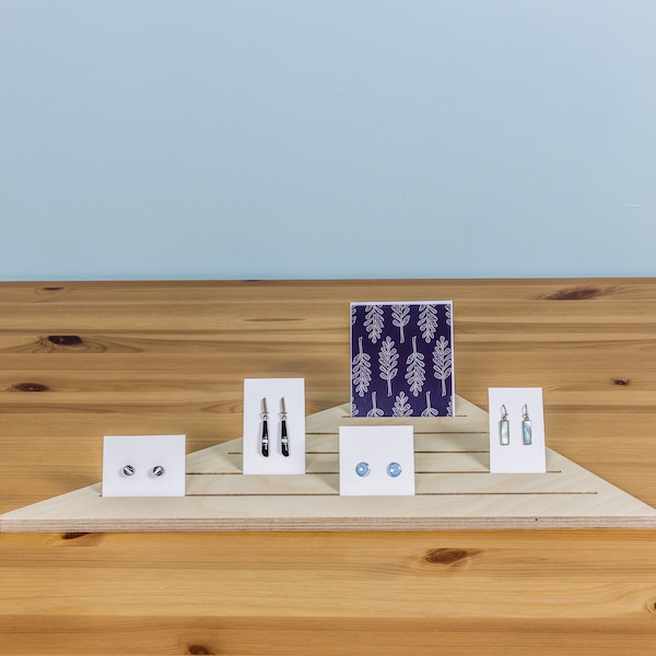 Expositor triangular de esquina con ranuras para tarjetas y joyas, ideal para comercios minoristas, ferias de artesanía y puestos de mercado.