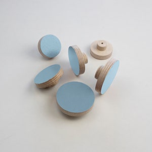 May include: Six light blue round wooden knobs with a natural wood finish. The knobs are approximately 5 cm in diameter.