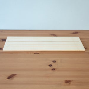 Pu&ograve; includere: Un tagliere di legno bianco con quattro scanalature parallele che corrono per tutta la lunghezza del tagliere.