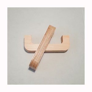 May include: Two wooden cabinet handles, one is a simple U-shape and the other is a long, thin strip. Both are made of light-coloured wood with visible grain.