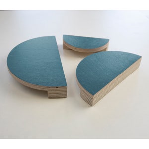 May include: Three teal blue semi-circular wooden cabinet knobs with a layered wood grain pattern.